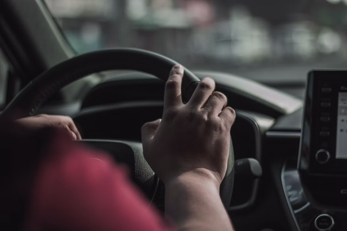 Driver with hands on the steering wheel on an open daylight road
